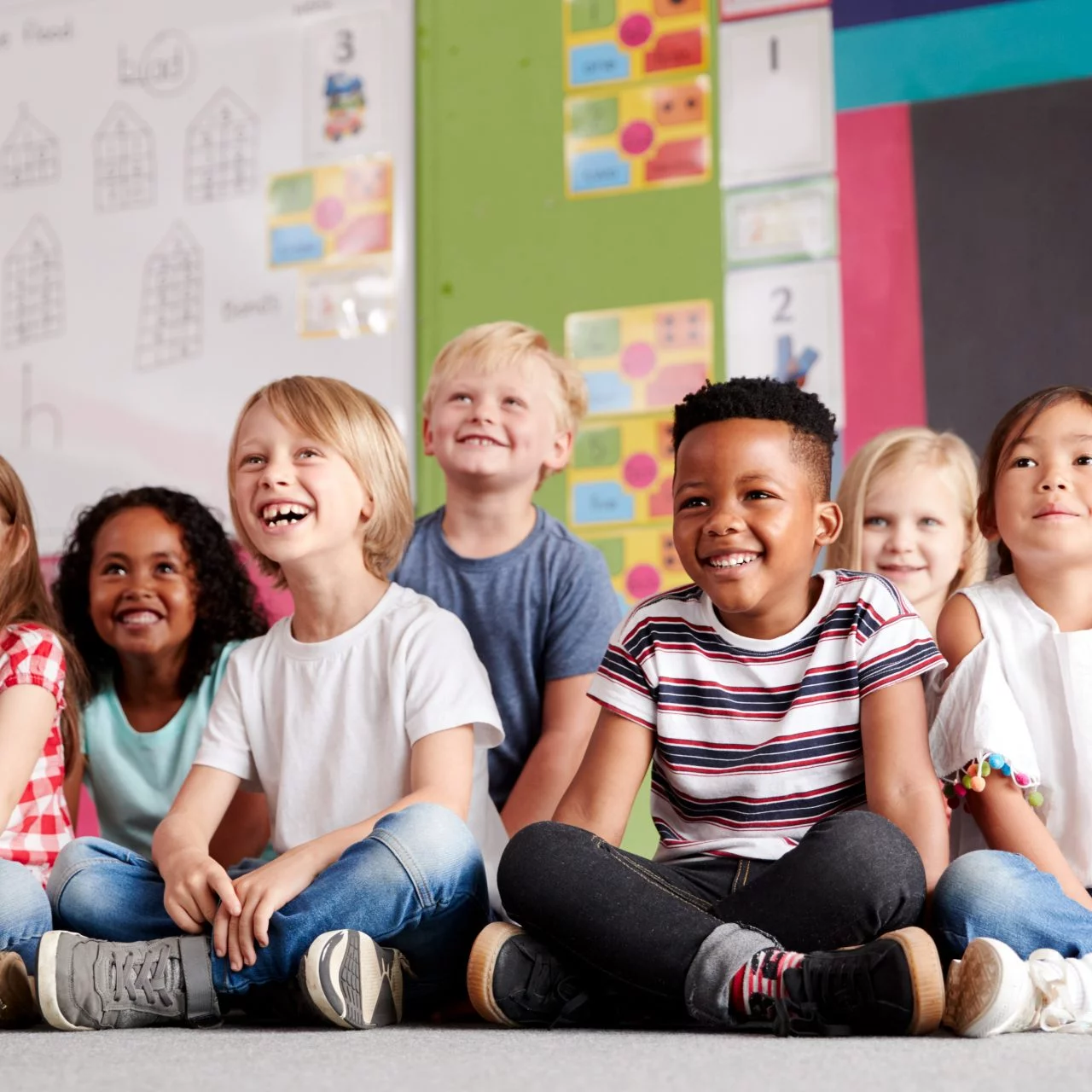 Group of kindergarten students laughing sitting on the floor of their classroom